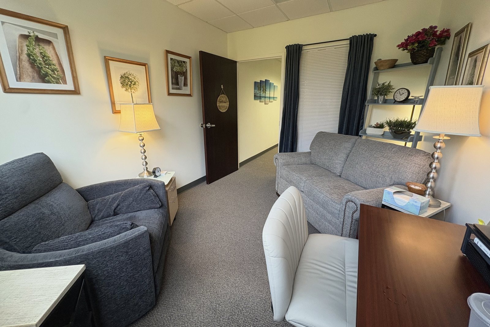 A therapy room at the Shelton office with a gray armchair, a sofa and two table lamps