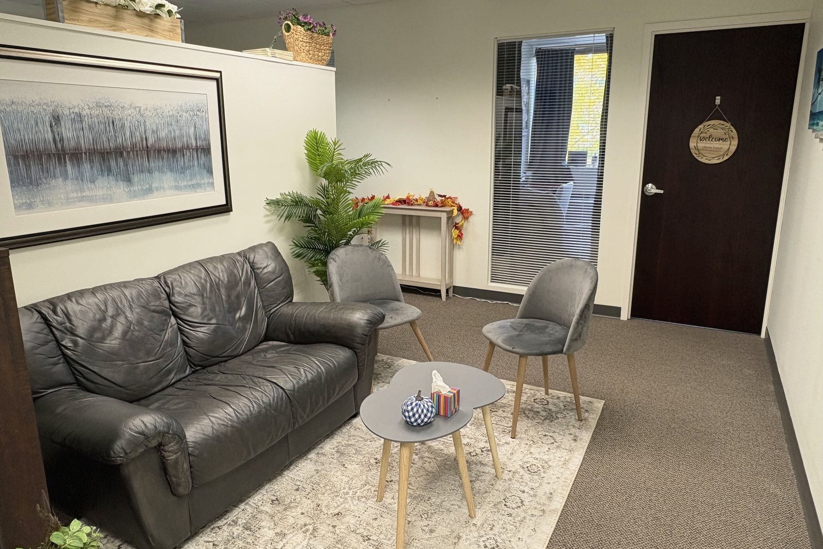 The waiting area at the Shelton office with a leather sofa, two gray chairs and a small table